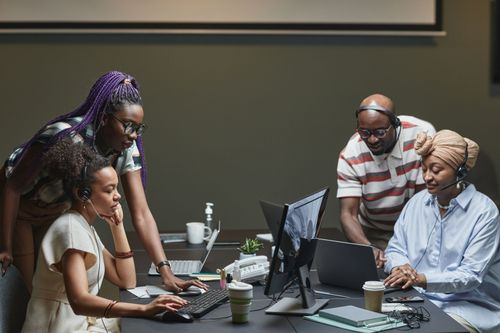 Team members collaborating around computers and documents